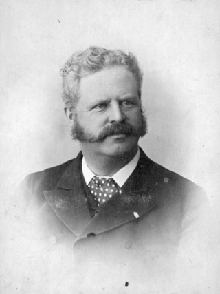 Black and white portrait of a man with a mustache in a buttoned up jacket.  