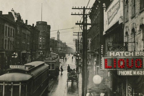 Black and white photograph of Yonge St., Queen to College Sts., looking north from north of Granby St. A sign for Hatch Bros. Liquor has been digitally coloured red.  