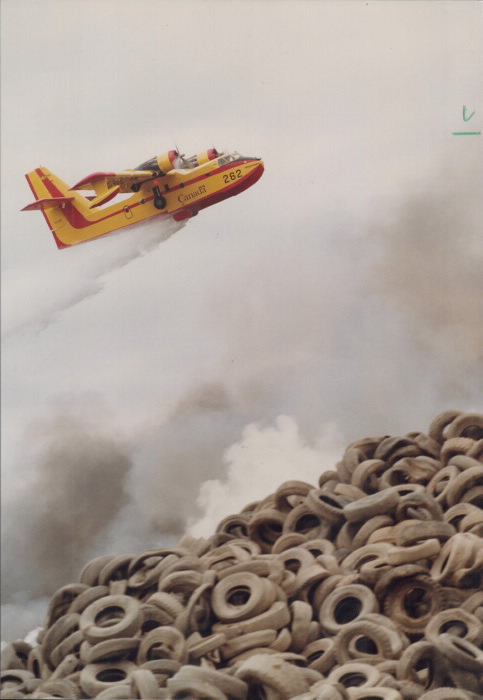 Airplane dropping water over a pile of smoking tires Airplane dropping water over a pile of smoking tires