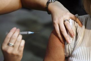A nurse injects a patient with a flu shot. The Canadian Press-Jeff McIntosh CityNews