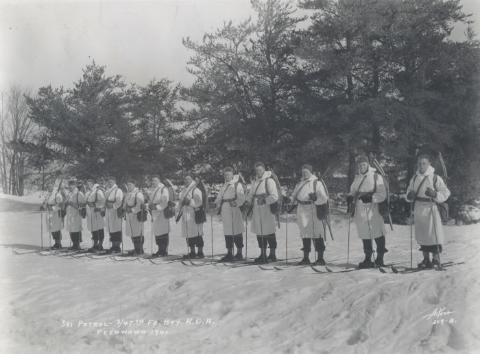 Men in ski gear standing in a line posing for photo