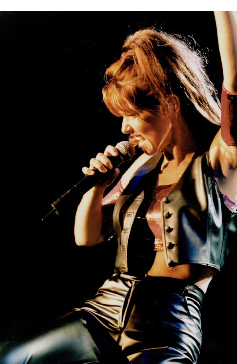 Woman singing into microphone one arm raised Woman singing into microphone one arm raised