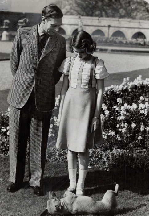 Man and young girl looking down at a dog on his side