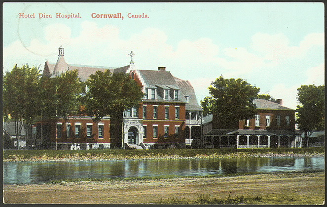 Postcard of large brick building among trees by some water