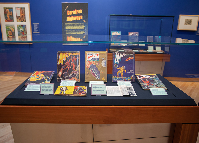 Museum glass display case with books and science fiction items inside Museum glass display case with books and science fiction items inside