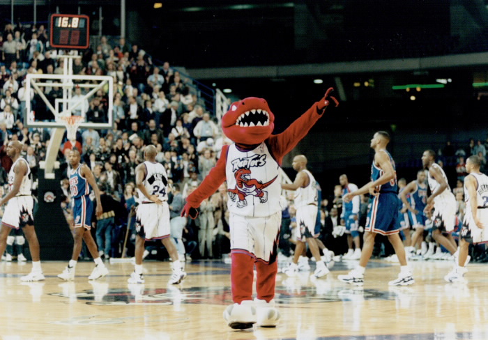 Raptors mascot with team behind it pointing out to crowd