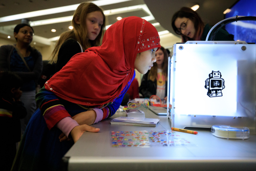 Girl's face illuminated by the glow of a 3D printer
