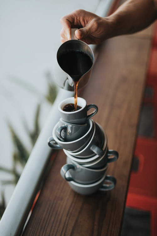 Coffee being poured onto a stack of balancing cups. 