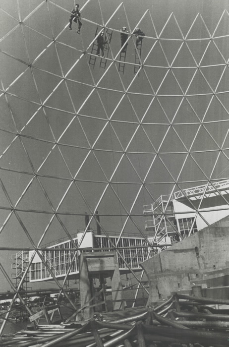 Structure de la grande sphère en construction avec des travailleurs suspendus à des échelles