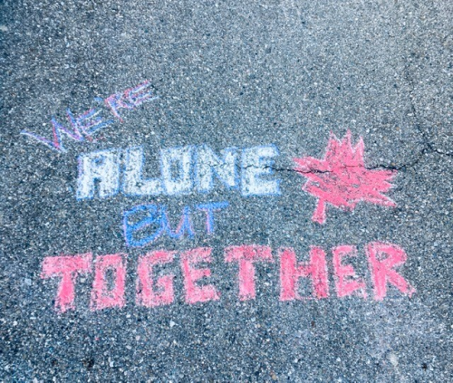Chalk drawing of words "We're Alone but Together"
