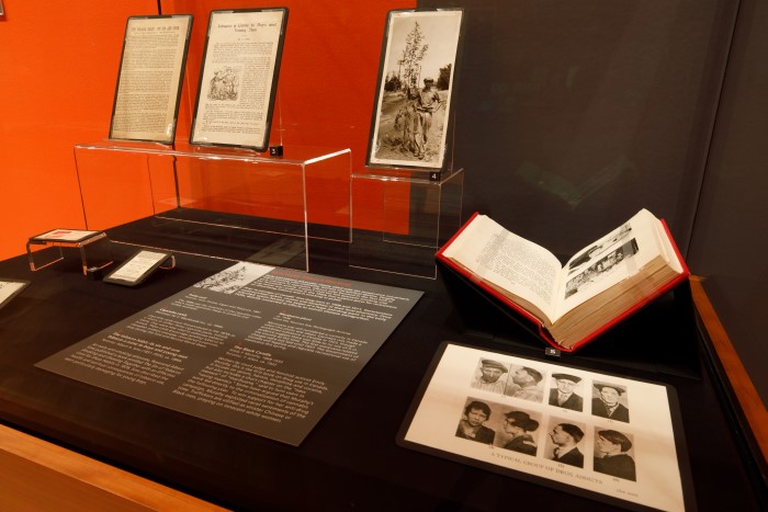 A glass display case includes photograph, books and ephemera related to smoking and illegal drugs in Canada. A book is displayed open at right. A reproduction of a plate is visible that is titled "A Typical Group of Drug Users"