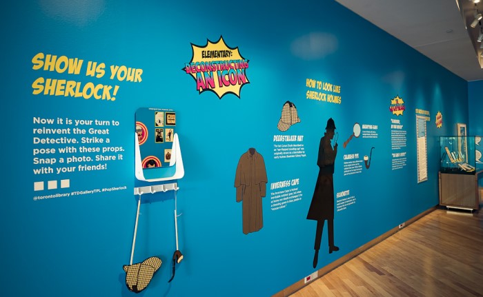 Interior of Pop Sherlock exhibit in gallery. Text on wall invites visitors to "Show Us Your Sherlock" and selfie props are displayed.