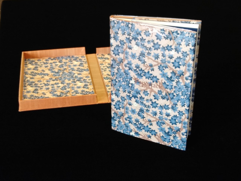 A book covered in Japanese paper alongside an open clamshell box lined with the same paper. 
