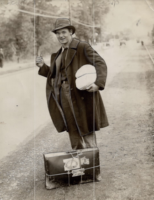 Mean with possessions standing on road with thumb up