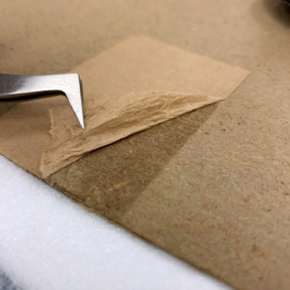 brown tape being removed from paper with tweezers