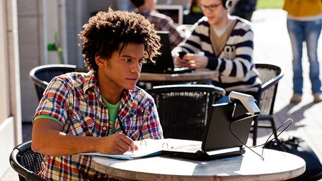 Young man using laptop at outdoor cafe