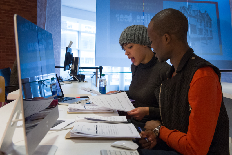 Two adults using a Mac computer.