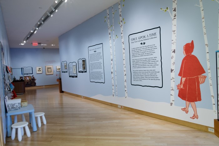 Installation image of Once Upon a Time exhibit showing large decal of Little Red Riding Hood walking in the woods