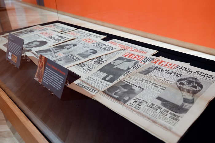 A display case with multiple copies of tabloid newspaper "Flash." 