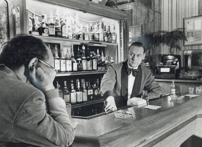 1975 Toronto Star Archives photograph showing Listening to a customer's problems is part of the day's work for barman Alfons Demleitner; who works at the Walker House Hotel