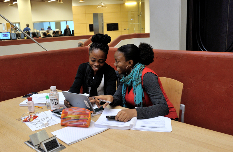 Young women working on tablet at library Young women working on tablet at library