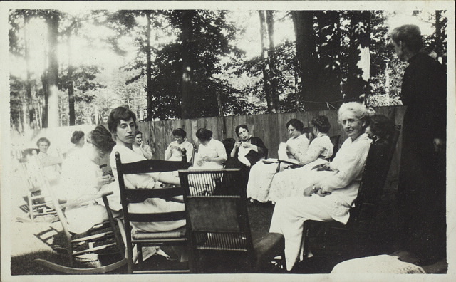Women sitting in circle outdoors on rocking chairs knitting