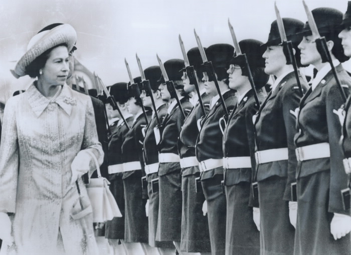 Queen walks by women in uniforms holding rifles
