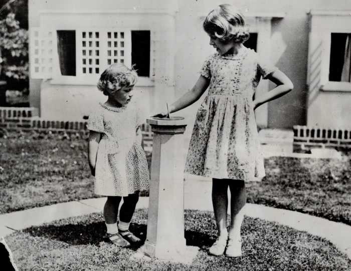 Two young girls standing outside by sundial