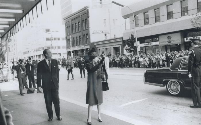The Queen waves to a street of onlookers as she is about to enter a building