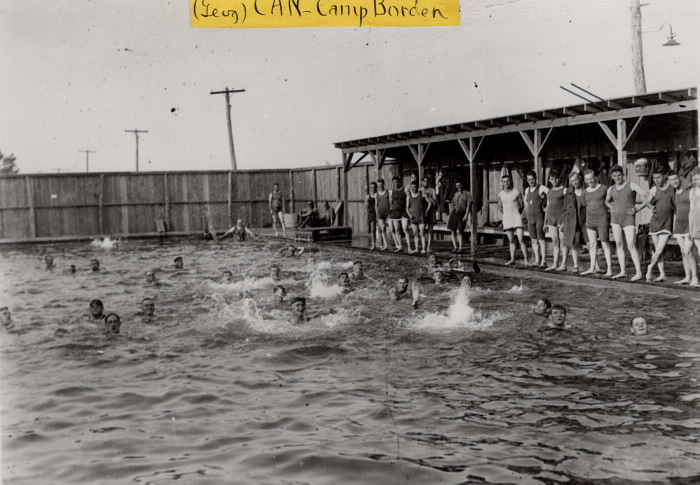 Pool built of wood in remote area with young men in splashing in place and looking on from the side