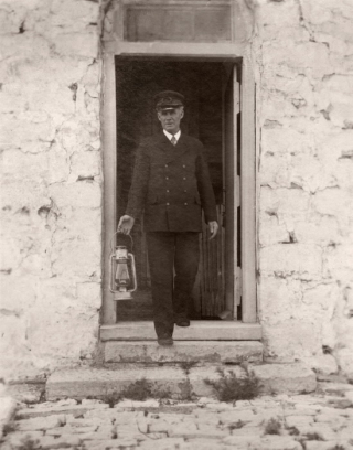 Man in uniform holding lantern coming out of door Man in uniform holding lantern coming out of door