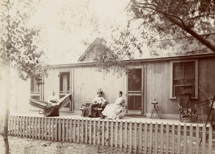 Vintage photo of three women sitting outside a cottage