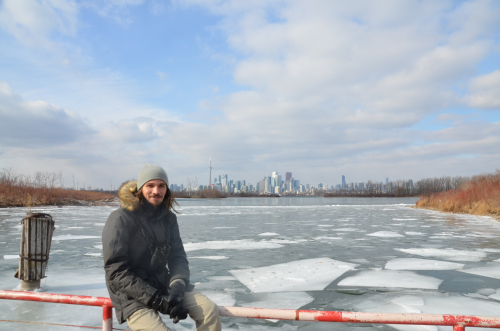 Andrés in front of a frozen lake and the Toronto skyline in the winter Andrés in front of a frozen lake and the Toronto skyline in the winter