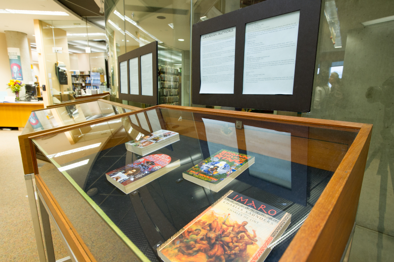 A close up of a display case from an exhibit in the Merril reading room. In the background you can see the Merril reference desk.