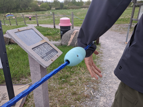 A person navigates the park by holding their wrist along a trail guide rope.