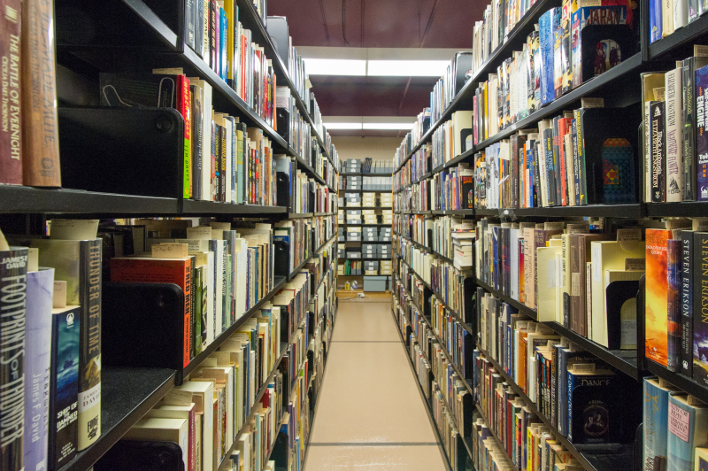 An aisle of compact shelving in the Merril Collection showing hundreds of books on either side An aisle of compact shelving in the Merril Collection showing hundreds of books on either side