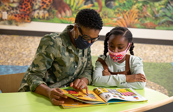 Mother and child reading wearing masks