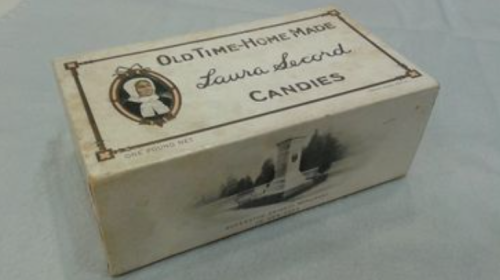 Photo of box of candies with Laura Secord image and text reading Old Time Home Made Laura Secord Candies and image of monument