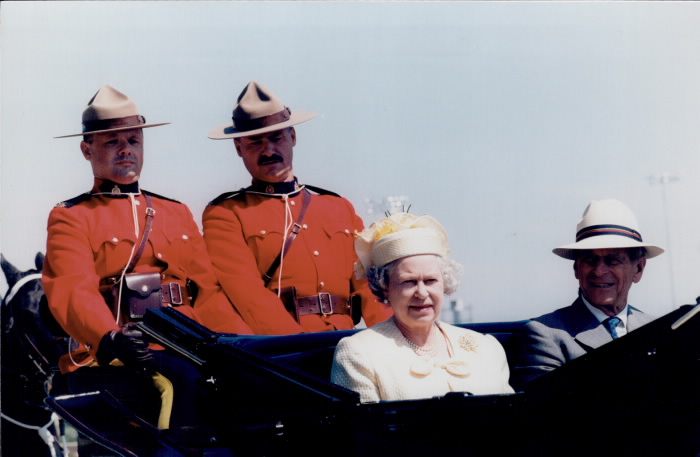 Two mounties in cart with Queen and her husband