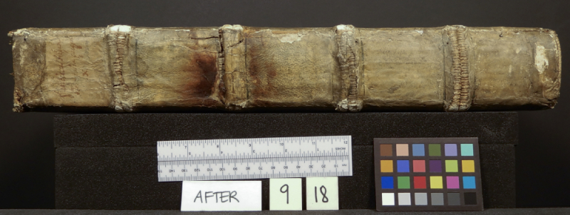 Spine of book with a few tears and measurement instruments below and paper reading After