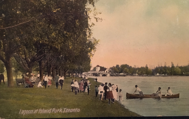 Vintage postcard of children and others by the water and a canoe approach and the words Lagoon at Island Park Toronto