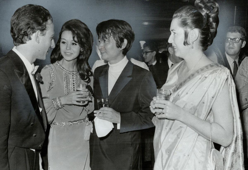 Four formally dressed individuals speak at indoor party