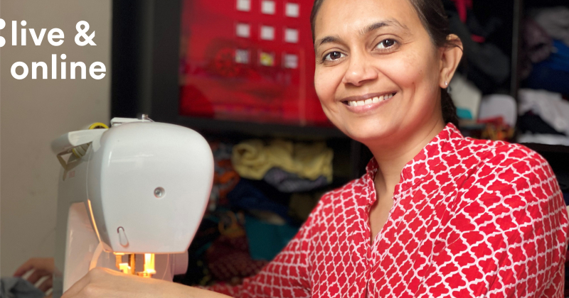 A woman in front of a sewing machine smiling.