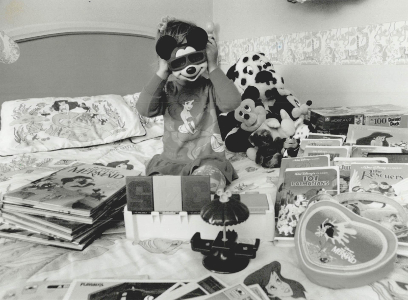 Black and white photography of a little girl surrounded by Disney merchandise