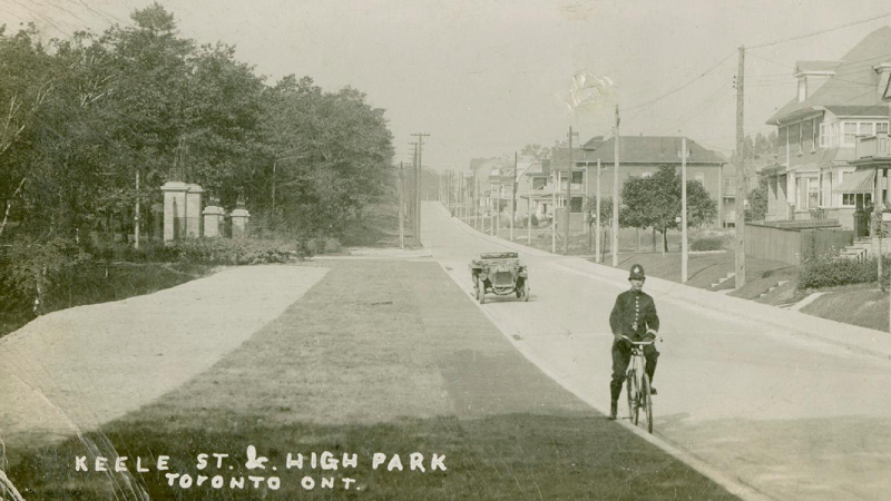 Postcard reading Keele St. & High Park Toronto Ont. and showing police officer on bike in residential street from the past 