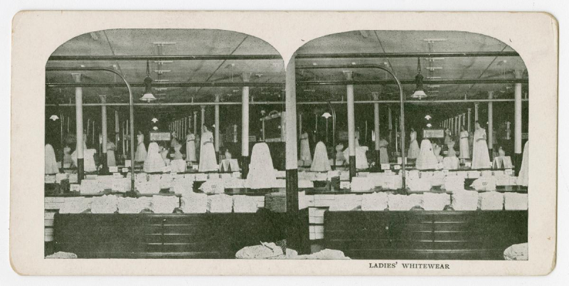 Interior of vintage building showing two side by side images of white dresses in large space with text below reading ladies whitewear
