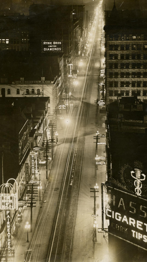 Brightly lit long street running through dark city with a few billboards Brightly lit long street running through dark city with a few billboards