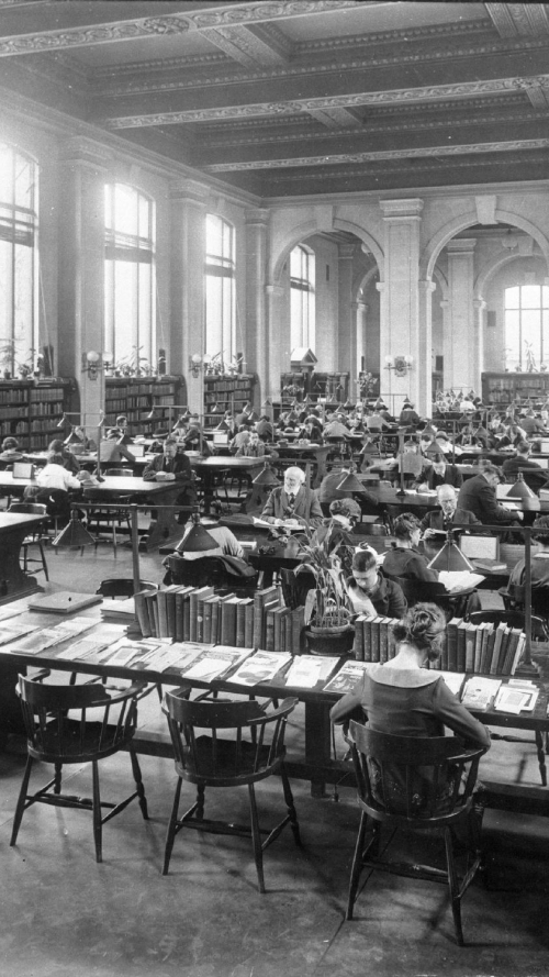 Vintage interior of library with many reading tables full of people sitting and reading in wooden chairs Vintage interior of library with many reading tables full of people sitting and reading in wooden chairs