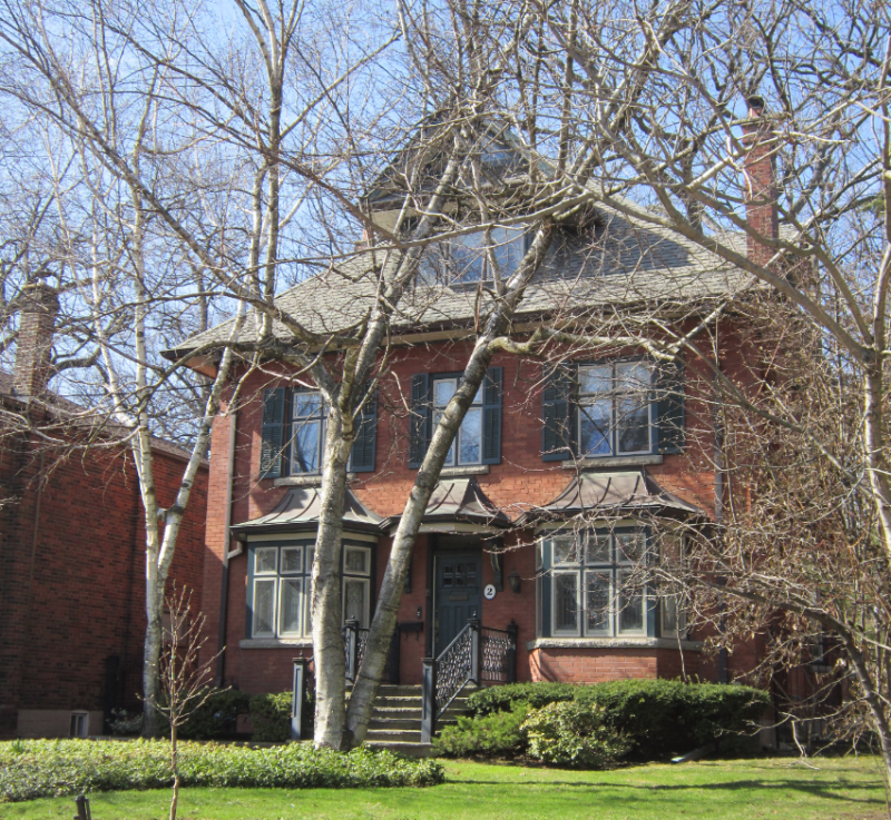 Modern day photo of large old brick house with trees in front