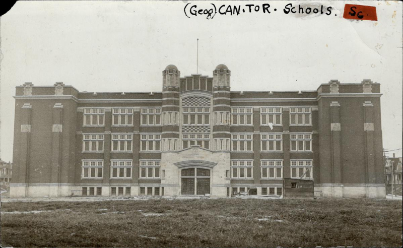 Faded photo of large school with grassy field in front and an inscription of abbreviations